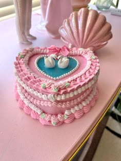 a heart shaped cake on a table with seashells in the shape of hearts