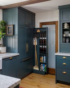 a kitchen with blue cabinets and white counter tops, gold pulls on the cupboards