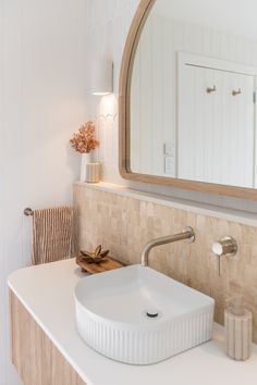 a bathroom sink sitting under a mirror next to a wooden towel dispenser