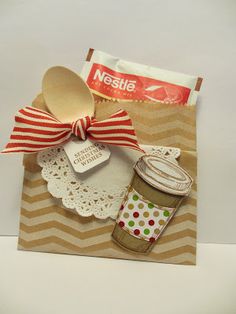 a paper bag with a spoon and cup on it, tied to a ribbon that says nestia