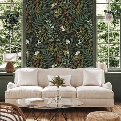 a living room filled with furniture and walls covered in green plants on the wallpaper