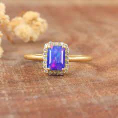 a ring with an amethyst colored stone surrounded by diamonds on a wooden surface