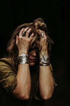 a woman with her hands on her head and two bracelets around her neck, covering her face