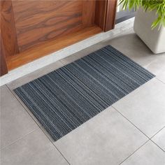 a potted plant sitting on top of a door mat next to a wooden door