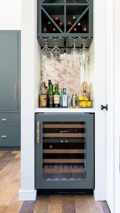 an open wine cabinet with bottles and glasses on the top, in front of a wooden floor