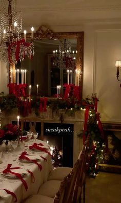 a dining room table set for christmas dinner with candles and red ribbon on the table