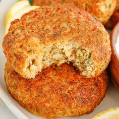 two crab cakes on a plate with lemon wedges