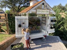 a little boy that is standing in front of a small building with plants on it