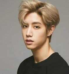 a young man with blonde hair wearing a black t - shirt and looking at the camera