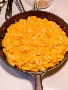 a skillet filled with macaroni and cheese on top of a white table