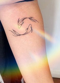 a woman's arm with a tattoo on it and a rainbow in the background