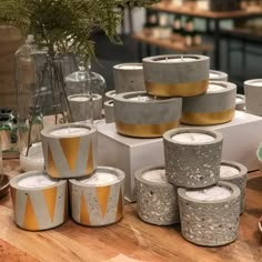 many different types of candles sitting on top of a wooden table next to vases with flowers in them