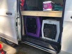 a van with its doors open and two dogs in their kennels