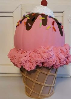 an ice cream cone with pink icing and sprinkles on top, sitting in front of a white door