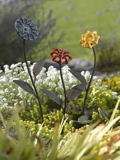 three metal flowers are in the grass