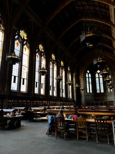 people are sitting at tables in the middle of a large room with stained glass windows