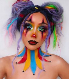 This Halloween makeup look is all about vibrant colors and dramatic flair. The base features bright rainbow hues blended seamlessly, with bold black lines to create a striking contrast. The hair is styled in playful buns with colorful streaks to match the makeup.   Photo credit by: @makeupcertified Jester Makeup, Cute Clown Makeup, Circus Makeup, Creative Halloween Makeup, Scary Clown Makeup, Cute Halloween Makeup, Halloween Makeup Ideas, Halloween Makeup Pretty, Cool Halloween Makeup