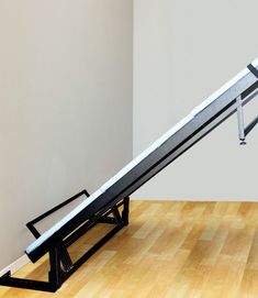 an escalator in the middle of a room with wood floors and white walls