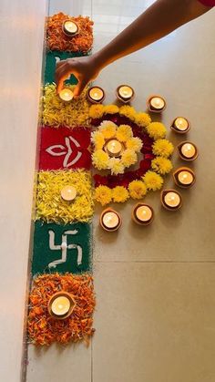 a person placing candles on the ground in front of flowers and other decorations that are arranged around them