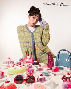 a woman sitting at a table with many purses and handbags