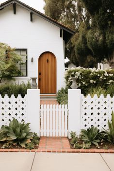 a white house with a wooden door and picket fence