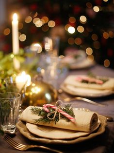 a table set for christmas dinner with candles and decorations