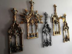 four ornate gold and silver wall hangings on a gray wall with white walls in the background