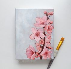 a person holding a paintbrush next to a painting with pink flowers on it