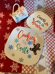 two plates with christmas sayings on them sitting on a red and white tablecloth