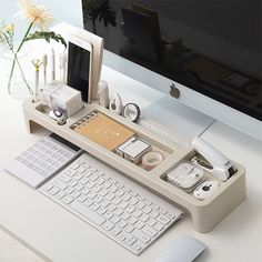 a computer desk with a keyboard, mouse and cell phone on it in front of a monitor