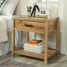 a nightstand table with books on it next to a bed