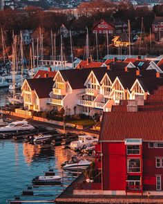 the boats are docked in the harbor by the red building with white trim on it