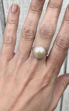 This elegant and stately pearl ring is made from a beautiful and unique white cream 14mm Mabe South Sea AAA Pearl that has many hues including pink. The pearl has been set in sterling silver with a sterling silver ring band handmade from half dome wire. This ring has some height, the setting is almost 1/2 inch high. The white cream pearl is more matte than the other mabe pearls listed, but still has a luminescent quality that makes it captivating!Made to order! Choose your size and your color pe Elegant Mother Of Pearl Round Rings, Classic Mother Of Pearl Round Rings, Classic Mother Of Pearl Rings, Elegant Oval Mother Of Pearl Ring, Elegant Round Mother Of Pearl Ring, Formal Mother Of Pearl Round Ring, Wedding Pearl Ring In Mother Of Pearl, Wedding Pearl Ring With Mother Of Pearl, Formal Round Mother Of Pearl Ring