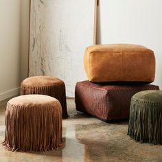 three foot stools with fringe on them in front of a white wall and floor