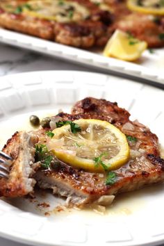 two white plates topped with meat and lemon slices