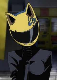 a person wearing a yellow helmet and black jacket in front of a building with a cat on it's face