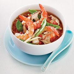 a white bowl filled with shrimp and veggies on top of a blue plate