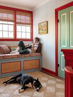 a man sitting on a bed next to a black and white dog laying on the floor