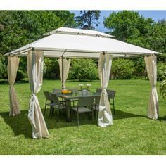 an outdoor gazebo with curtains on the sides and tables in the back ground, surrounded by green grass