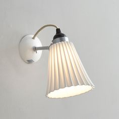 a wall light with a white shade hanging from it's side on the wall