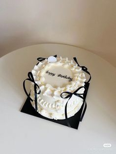 a white cake with black ribbon around it