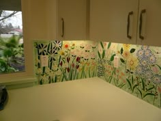 a kitchen counter with flowers painted on the backsplash and cupboards behind it