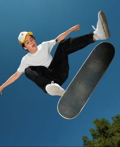 a young man in the air with a skateboard and wearing a yellow hat is doing a trick