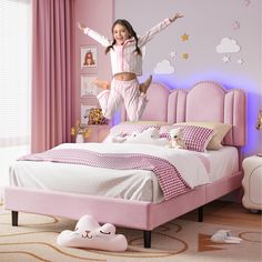 a girl jumping in the air on her pink bed