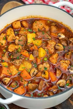 a pot filled with stew and vegetables on top of a wooden table