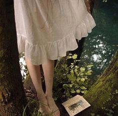 there is a woman's feet in the grass next to a book and trees