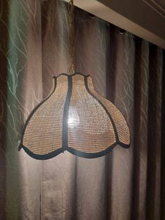 a lamp hanging from the ceiling in front of curtains