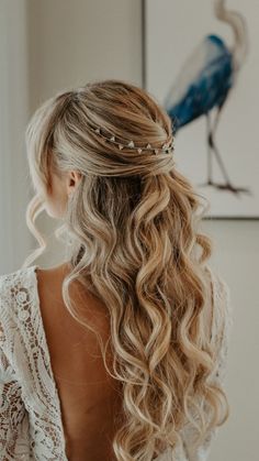 a woman with long blonde hair wearing a white dress and a bird on the wall behind her