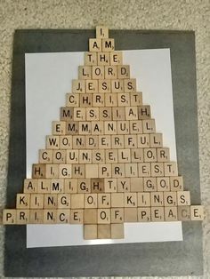 a wooden scrabble christmas tree with words written on the top and below it