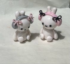 two white ceramic figurines with black bows on their heads and ears, sitting next to each other